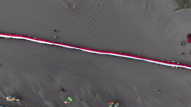 4K drone footage of Indonesia's 480-meter red and white flag unfurled at Parangtritis Beach, celebrating Indonesian Independence Day and national pride.