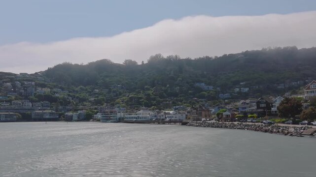 Drone shot of the green hills of Sausalito, California with clouds in the background