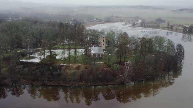 Grafsnas Castle Park beside Lake Anten with snowy trees and winter landscape, Sweden, aerial establishing orbit