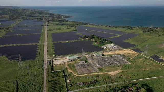San Carlos Negros Occidental aerial drone shot orbiting over 120 meters above the Aboitiz solar farm. The camera pans right to reveal the entire photovoltaic solar power plant facility, including oper
