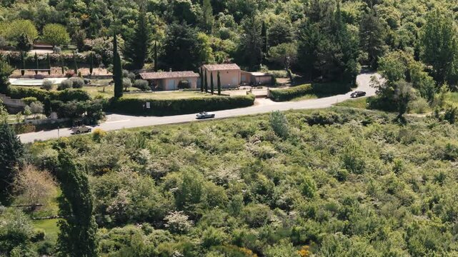 Classic cars sweep around a bend through springtime Provence