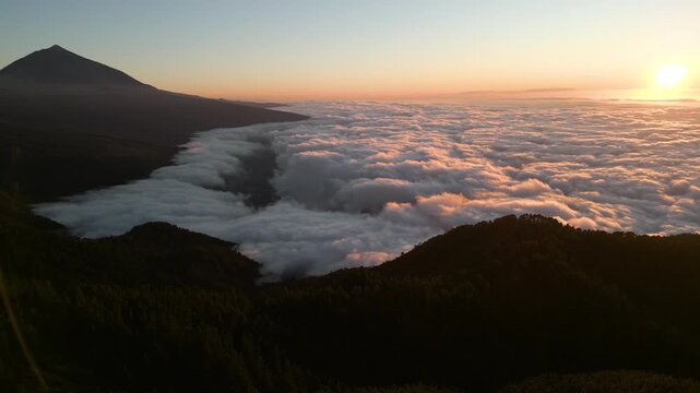 Sunrise over Teide volcano with clouds filling the valley below mountain slopes