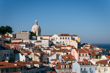 Fototapeta premium Cityscape of Alfama district with red tiled roofs and the National Pantheon dome under blue sky in Lisbon Portugal