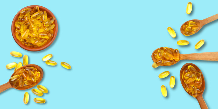 Omega 3. Spoonfuls of omega fish oil capsules scattered on a bright background.