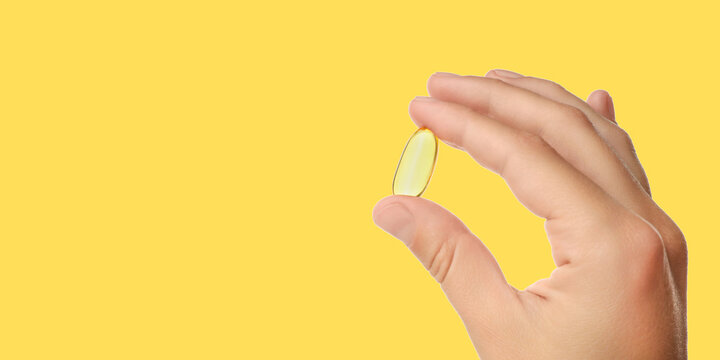 Omega 3. Hand presents omega 3 fish oil capsule in bright setting. Health and nutrition concept.