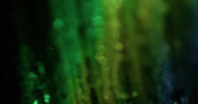 Bokeh lens. Gradient gleam. Defocused yellow green blue color foil texture optical flare light round flash on abstract dark black background.