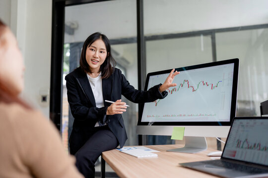 Young woman discussing business analytics and charts, managing finance and cryptocurrency trading in a modern office