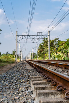 Low angle view of electrified railway track stretching into distance with overhead catenary wires