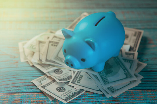 Blue piggy bank with money on blue wooden background, saving money concept