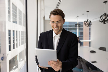 Smiling manager reading positive updates on tablet in urban office workspace monitoring task progress in professional app using modern digital tools on mobile device for easy business data analysis © fizkes