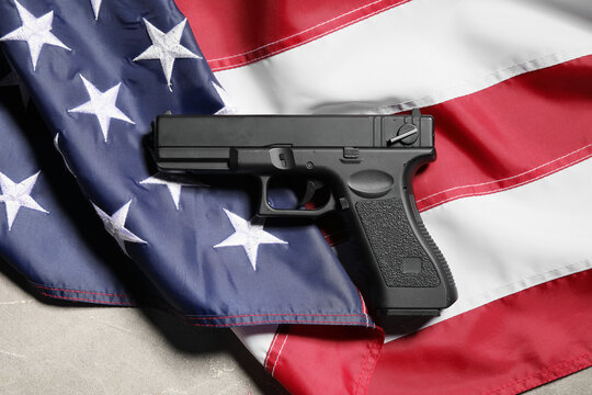 Gun control and second amendment debate, black handgun resting on a folded United States flag national security and constitutional rights