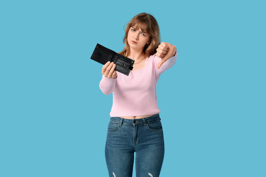 Young woman with empty wallet showing thumb-down on blue background
