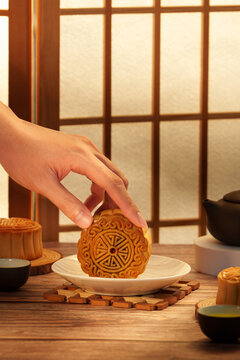 Cropped hand setting traditional mooncake on plate for Mid-Autumn Festival