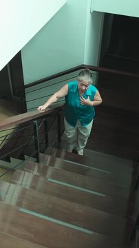 asian senior woman struggling to climb stairs due to weak body, panting and breathless while ascending at home, vertical video