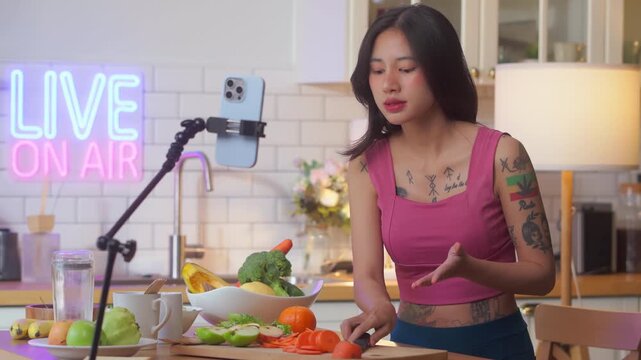 Content creator live streaming cooking show with neon "on air" sign, food vlogger gesturing while presenting fresh vegetables and fruits, healthy eating tutorial recording concept