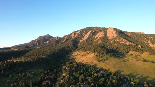 Aerial drone footage of the flatirons rock formations in boulder colorado during golden hour sunlight.