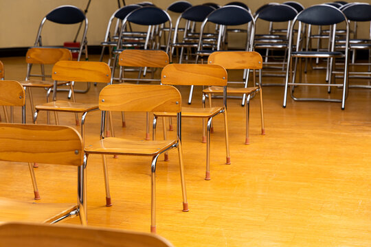Wooden chairs arranged in a classroom setting for an event in the afternoon