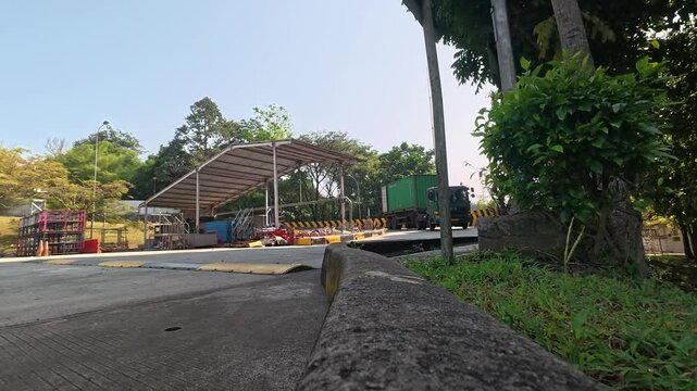 Green cargo truck driving through industrial facility security checkpoint
