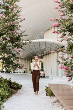 Korean woman strolling through a blooming pathway in an urban setting
