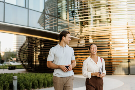 Korean woman and Caucasian man share a joyful walk near modern architecture