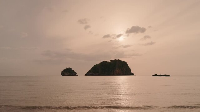 Golden hour tropical sea landscape with soft waves and islands silhouette.