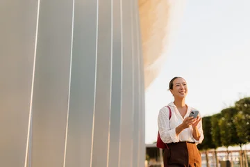 Korean woman enjoying a sunny day while using her smartphone outdoors © BGStock72