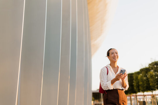 Korean woman enjoying a sunny day while using her smartphone outdoors