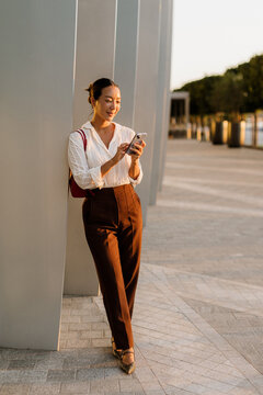 Korean woman enjoys a sunny evening while texting on her smartphone