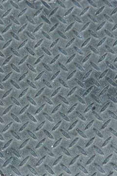 Surface of a diamond-patterned metal plate showing wear and texture in an industrial setting