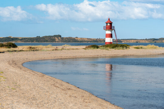 Griset&aring;odde Fyr, Griset&aring;odde Leuchtturm, Rot-wei&szlig;er Leuchtturm am Oddesund, leicht bew&ouml;lkter Himmel, Spiegelung im Wasser, horizontal 