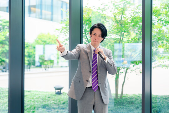 にこやかにマイクで話す男性のビジネスマン