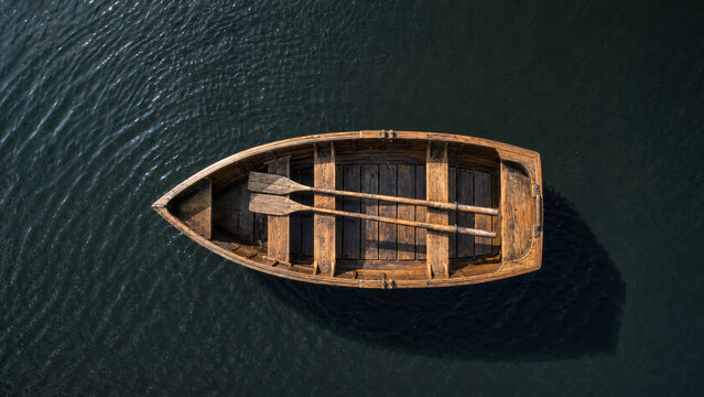 Wooden rowboat on dark water, top view