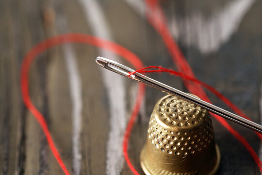 A Needle With Thread And A Thimble