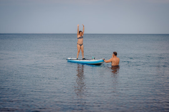Father teaching daughter paddleboarding on calm sea