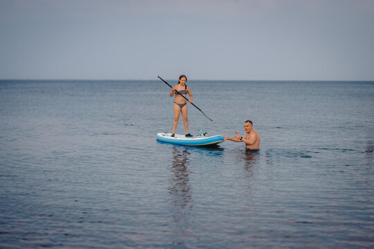 Father teaching daughter paddleboarding on calm sea