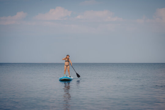 Woman paddleboarding on calm ocean water enjoying summer vacation