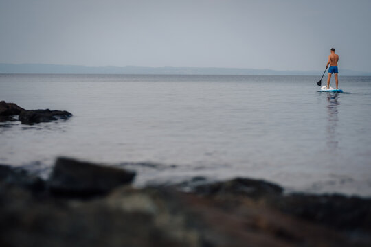 Man paddleboarding on calm ocean water, enjoying solitude