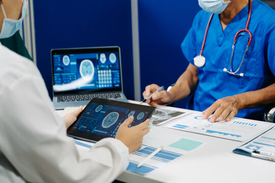 A dedicated medical team discusses patient diagnostics, reviewing brain MRIs and medical charts on digital devices