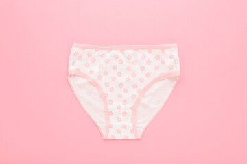 New white panties with pink flower pattern for little child girl on light pink table background. Pastel color. Closeup. Flat lay. Top down view. © fotoduets