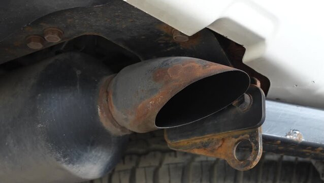 Rusty metal exhaust muffler tailpipe on a car underbody frame.