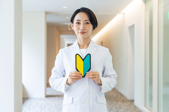 初心者マークを持つ白衣の女性。医師、病院、クリニック、資格、スキル、研修医、新人、採用、人手不足