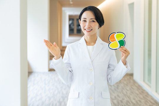 高齢者マークを持つ白衣の女性。医師、病院、介護、福祉、お年寄り、シニア、シルバー、支援、サポート