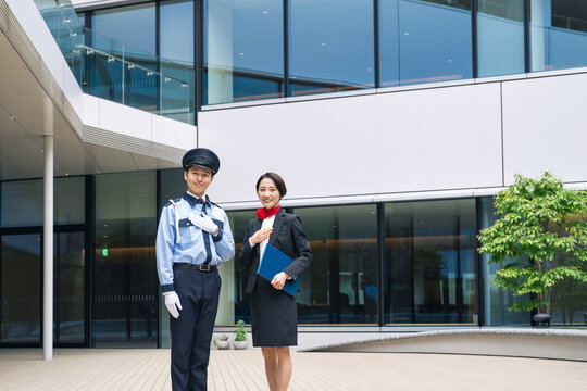 建物の前に立つ警備員とスタッフ。受付、案内、ホテル、ホテリエ、警備、セキュリティ、防犯、ビルメン