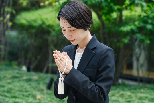 合掌する喪服の女性。墓地, お墓参り, 供養, 喪服, 葬式, 葬儀, 葬祭場, 樹木葬, 霊園