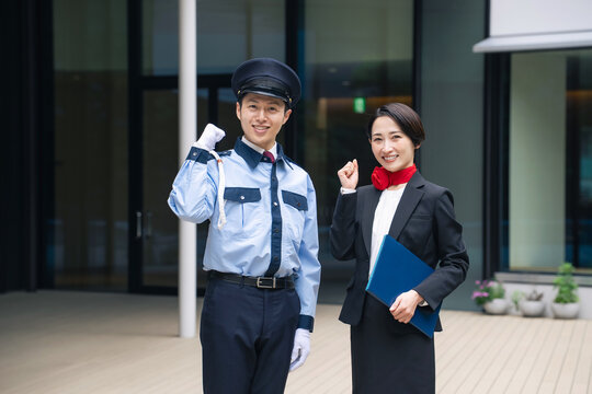 建物の前でガッツポーズする警備員とスタッフ。受付、案内、ホテル、ホテリエ、警備、セキュリティ、防犯