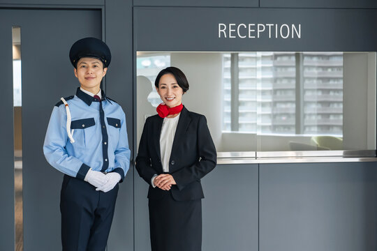 受付に立つ警備員とスタッフ。ホテル、ホテリエ、警備、セキュリティ、防犯、安全、仕事、施設、案内、企業