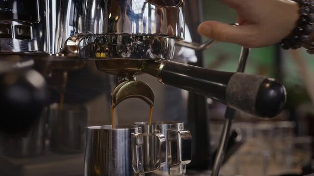 Espresso machine pouring rich coffee into metal pitchers while barista stops extraction process. Ideal for cafe advertising, barista tutorials, coffee brand promotions, restaurant commercials