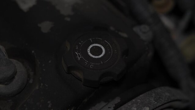 Black plastic engine oil filler cap on car valve cover.