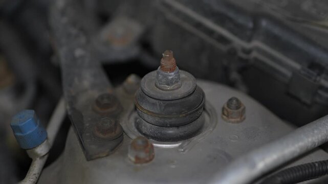 Car front suspension strut mount tower with rusty top nut.