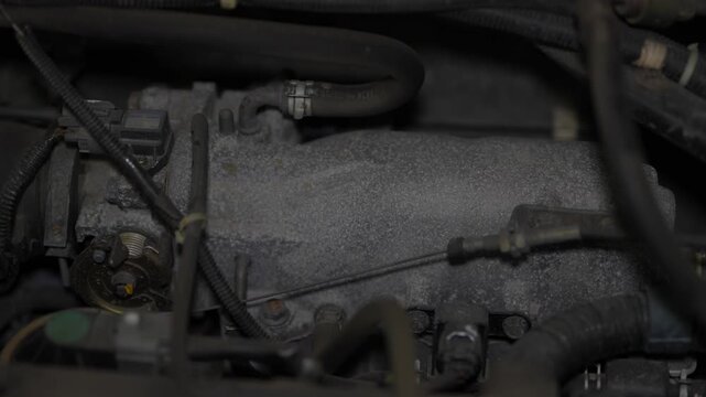 Car engine intake manifold assembly with throttle body and cables.